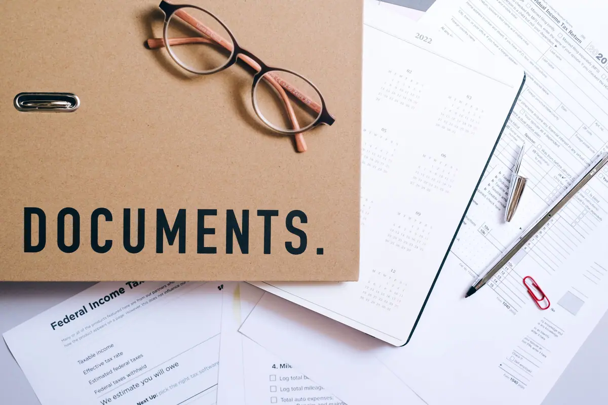 A document folder, forms and glasses on a desk