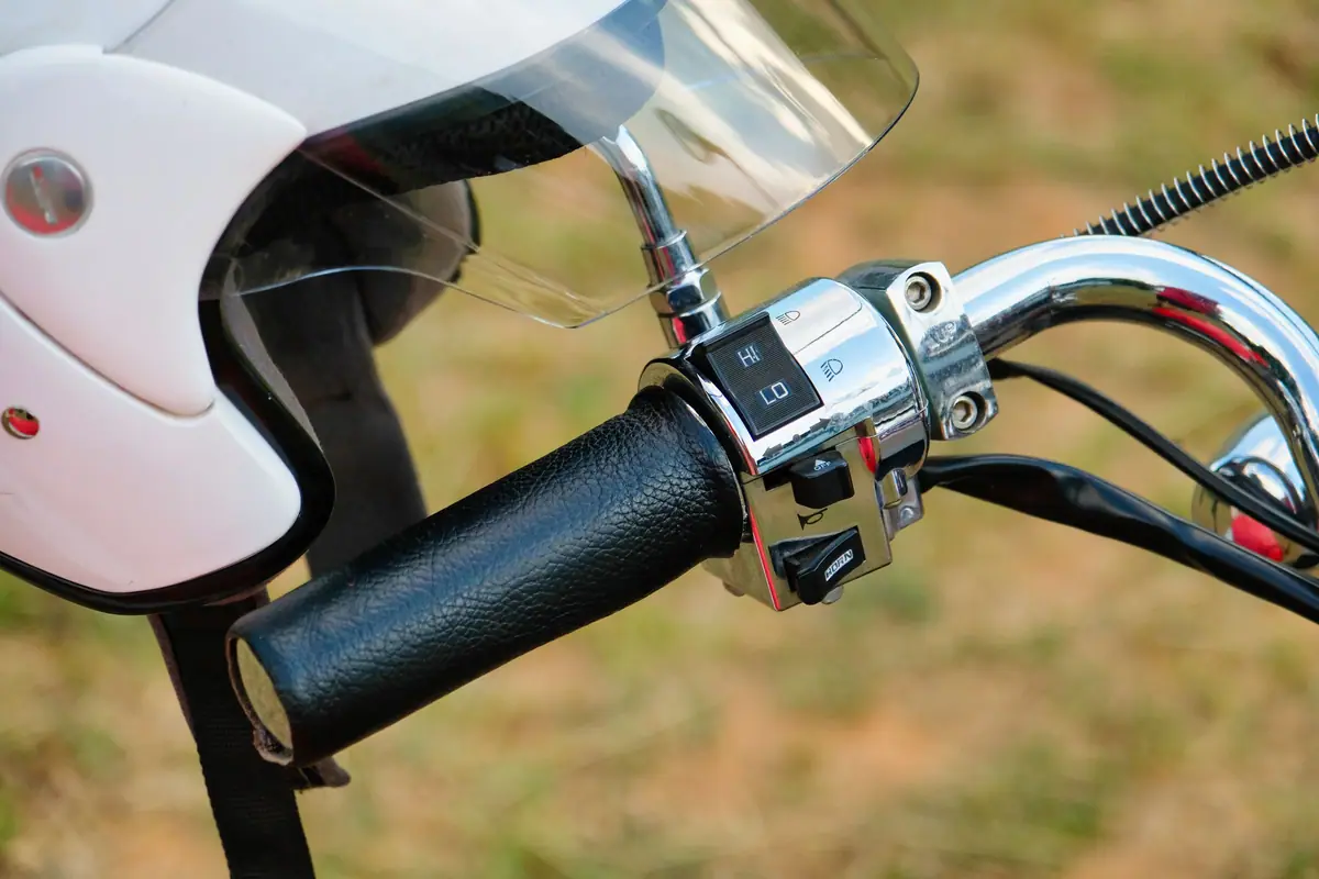 A helmet hanging on a motorbike handlebar