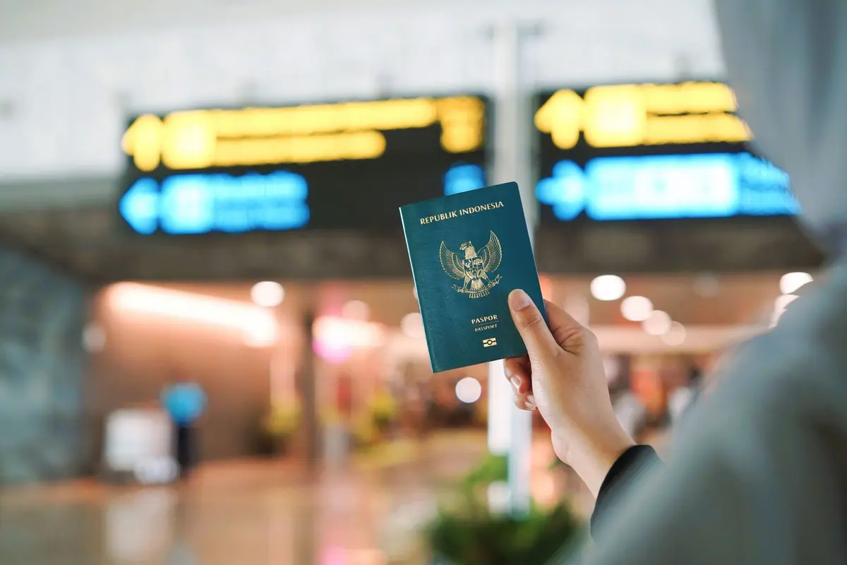 A traveller holding a passport in an airport terminal