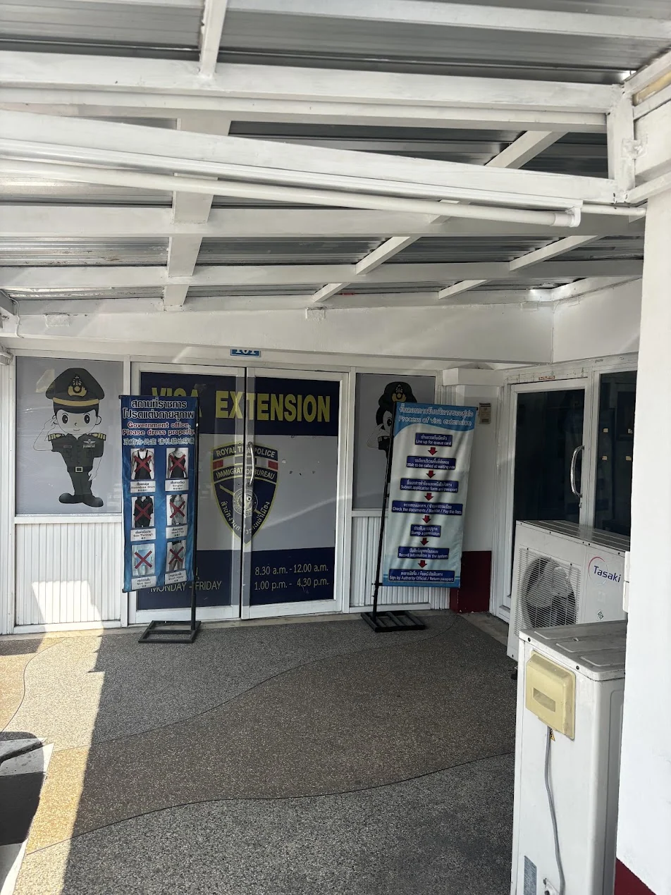 The VISA EXTENSION door at Phuket Immigration under the stairs, with opening hours on the glass
