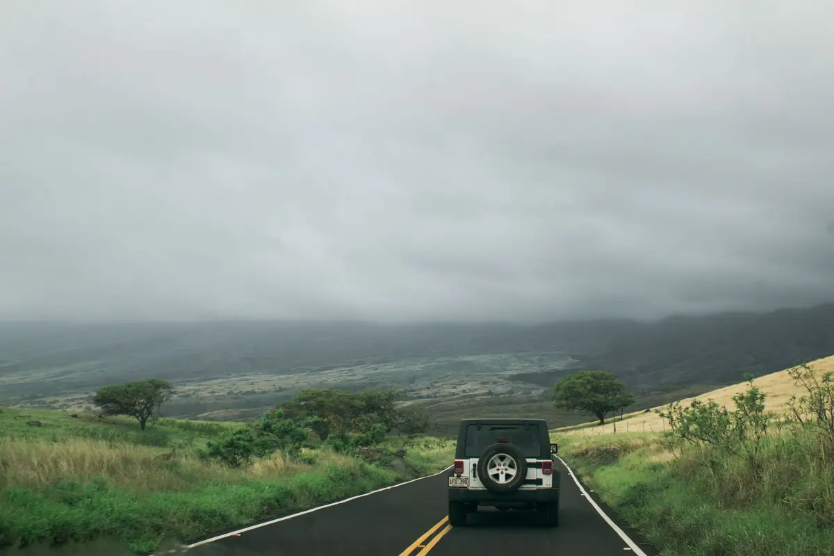 An off-road car on a winding road through green hills