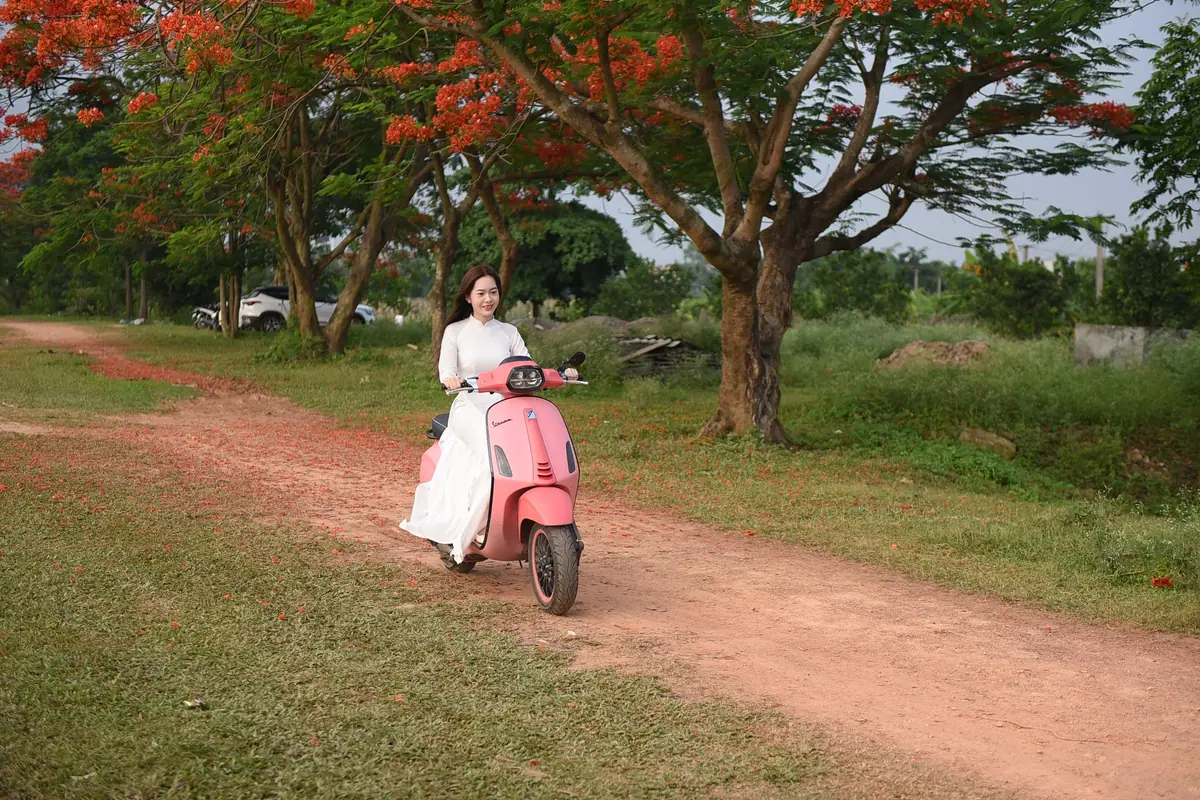 A woman riding a pink scooter along a path under trees