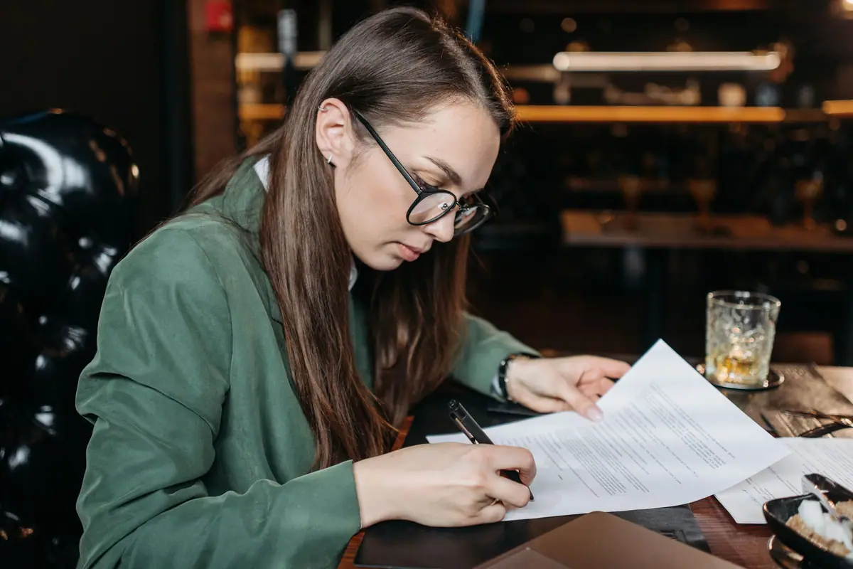 A woman filling in and signing documents at a desk